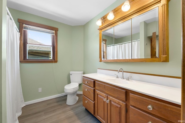 bathroom with vanity, baseboards, wood finished floors, and toilet