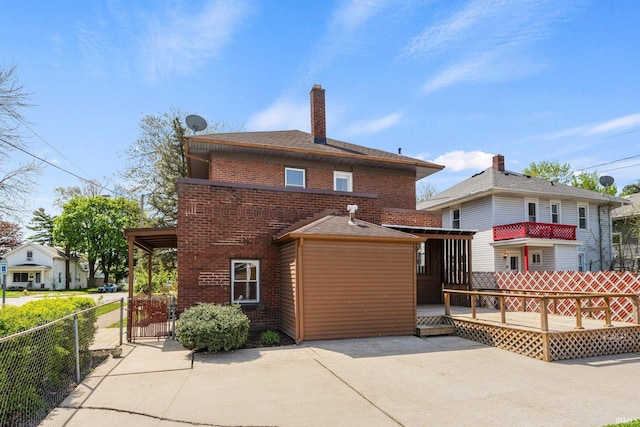 view of front of home featuring fence, a wooden deck, a patio, brick siding, and a gate