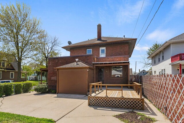 back of property with fence, brick siding, a wooden deck, a chimney, and a patio area