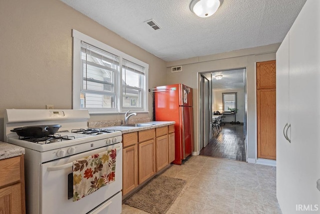 730 S Bell St, Kokomo, IN 46902 - kitchen with a textured ceiling, visible vents, a sink, freestanding refrigerator, and white range with gas cooktop