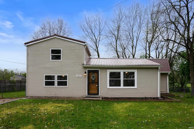 view of front of home with fence, metal roof, and a front yard
