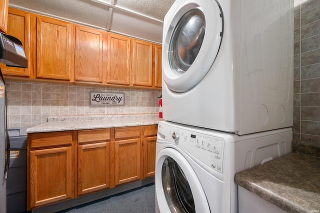 laundry area with stacked washer / drying machine and cabinet space