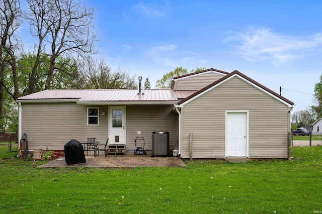 back of house with central AC, entry steps, a patio area, metal roof, and a lawn