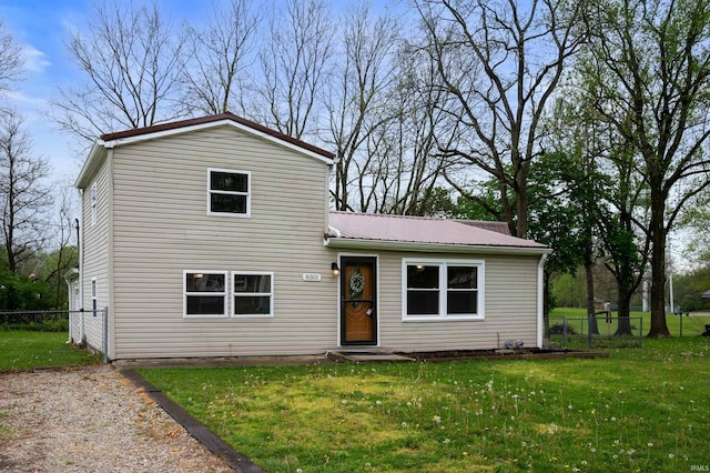 traditional-style house with fence, metal roof, and a front yard