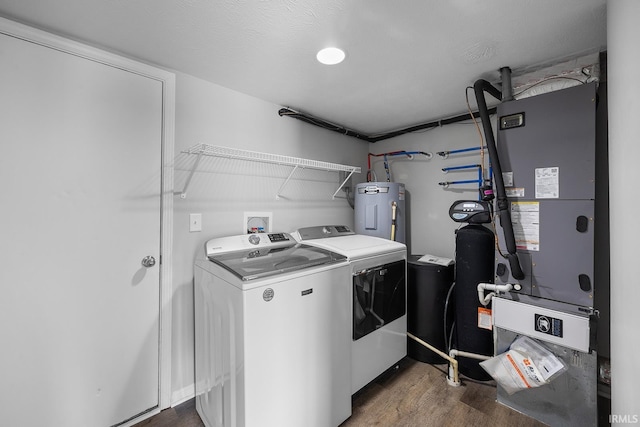 laundry room with electric water heater, laundry area, wood finished floors, heating unit, and washer and clothes dryer