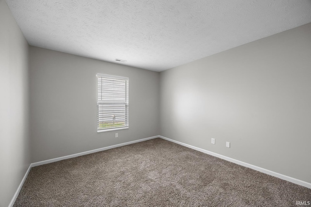 spare room with baseboards, carpet, a textured ceiling, and visible vents
