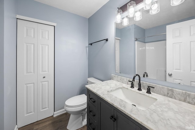 full bathroom featuring a closet, wood finished floors, toilet, and vanity