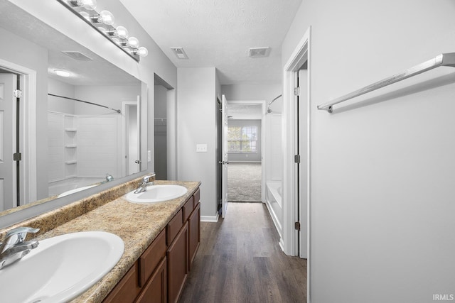 bathroom featuring visible vents, a sink, a textured ceiling, and wood finished floors