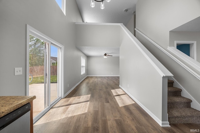 entryway with ceiling fan, a towering ceiling, wood finished floors, baseboards, and stairs