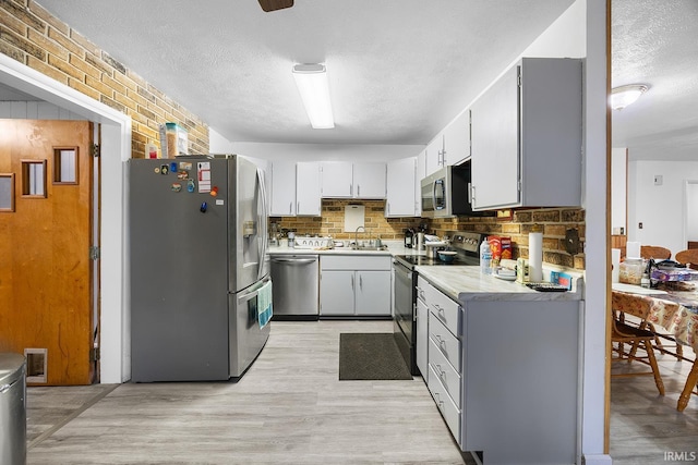 kitchen with light countertops, a sink, a textured ceiling, and stainless steel appliances