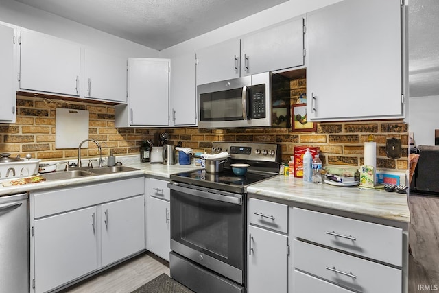 kitchen featuring light countertops, stainless steel appliances, decorative backsplash, and a sink
