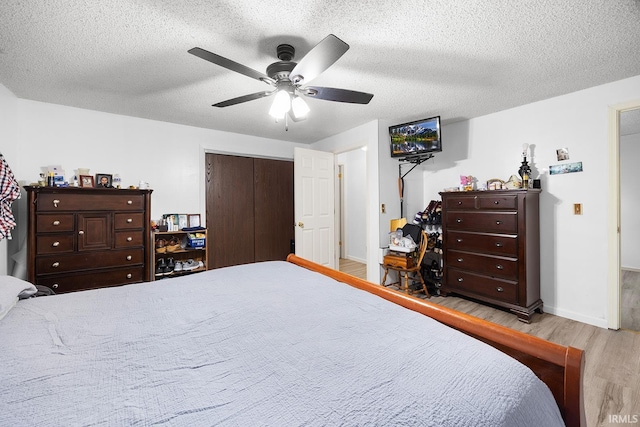 bedroom featuring baseboards, a textured ceiling, wood finished floors, and a closet