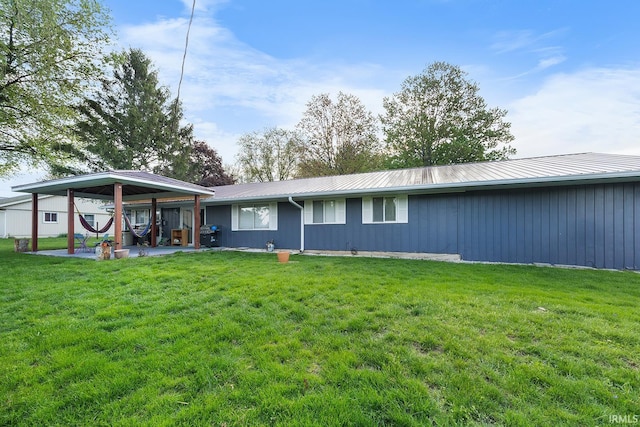 rear view of property with a patio, board and batten siding, a yard, and metal roof