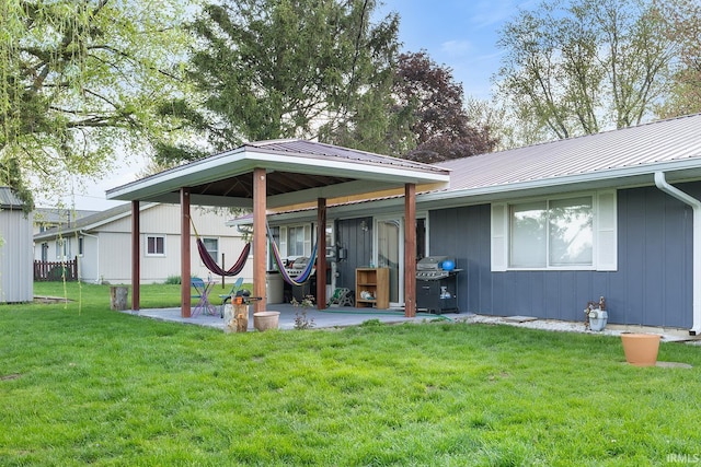 rear view of house featuring a yard, a patio area, and metal roof