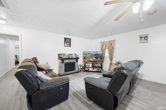 living room with baseboards, a textured ceiling, ceiling fan, and wood finished floors