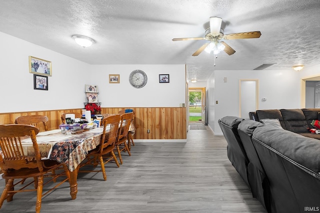 dining area with wood finished floors, wainscoting, a textured ceiling, and visible vents