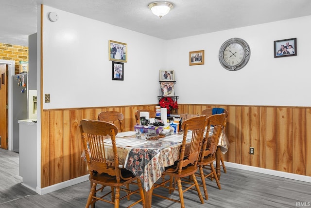 dining room with wood walls, wood finished floors, and a wainscoted wall