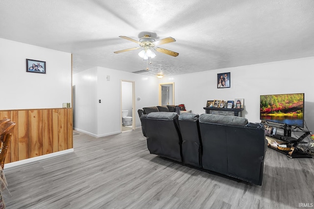 living area with visible vents, baseboards, a textured ceiling, a ceiling fan, and light wood-style flooring