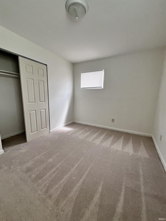 unfurnished bedroom featuring baseboards, carpet, and a closet