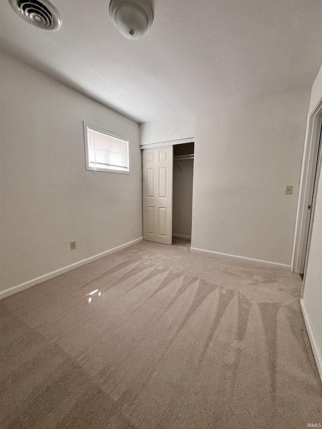 unfurnished bedroom with visible vents, baseboards, a closet, and light colored carpet