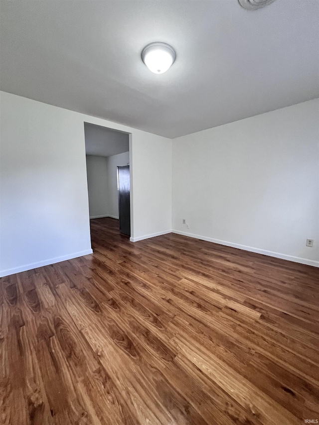 empty room featuring baseboards and dark wood-style floors