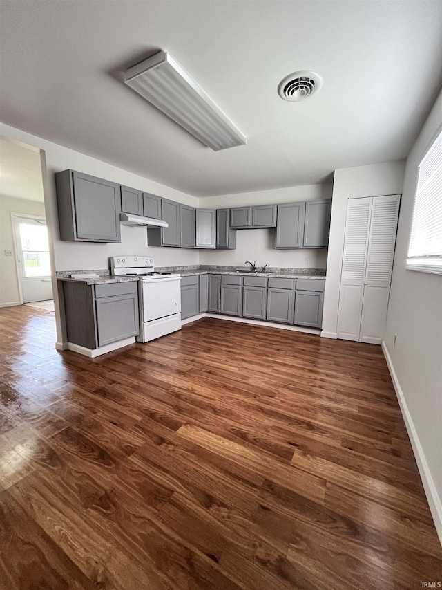 kitchen with dark wood-type flooring, gray cabinets, under cabinet range hood, and white range with electric cooktop