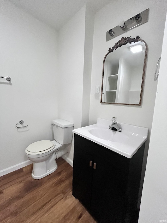 bathroom featuring baseboards, vanity, toilet, and wood finished floors