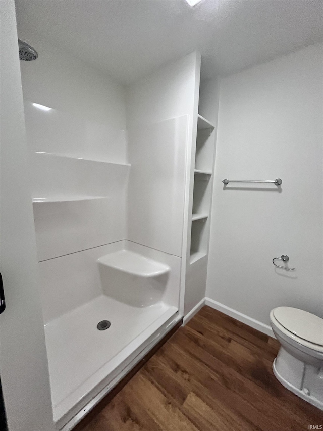bathroom with toilet, baseboards, walk in shower, and wood finished floors