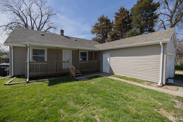 view of front of home with a shingled roof, covered porch, a chimney, and a front yard