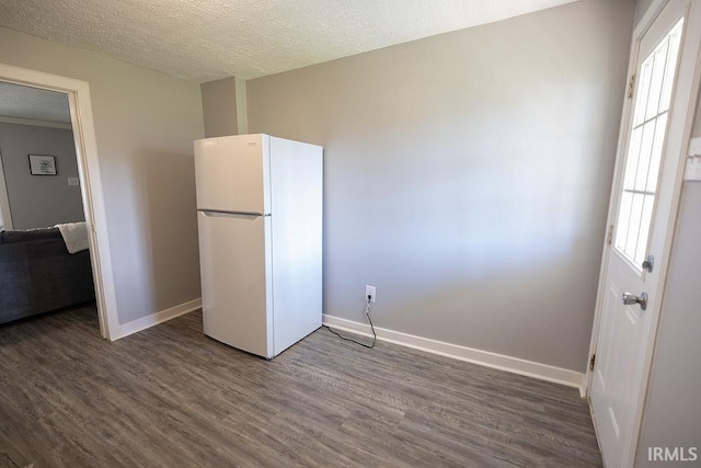 interior space featuring freestanding refrigerator, a textured ceiling, baseboards, and dark wood-type flooring