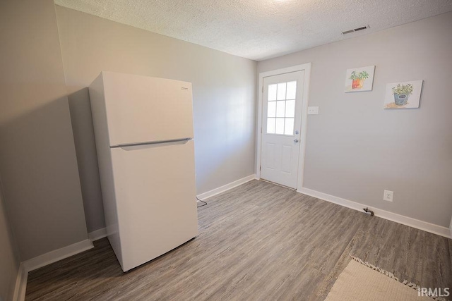 interior space with visible vents, baseboards, a textured ceiling, and wood finished floors