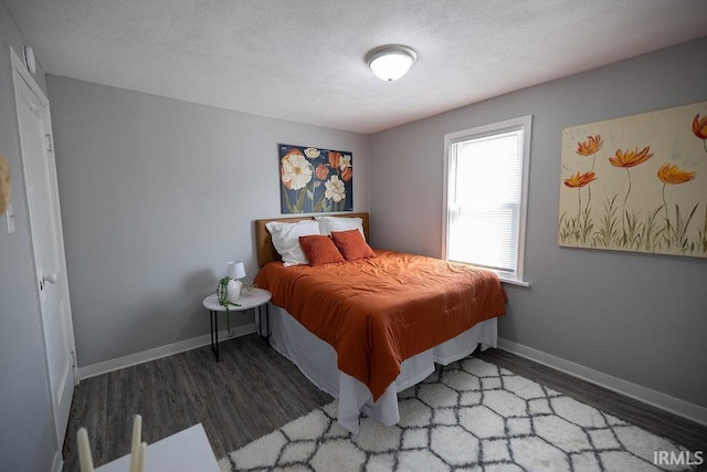 bedroom featuring baseboards, a textured ceiling, and wood finished floors