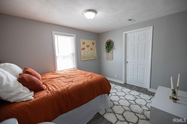 bedroom featuring baseboards, light wood finished floors, and visible vents