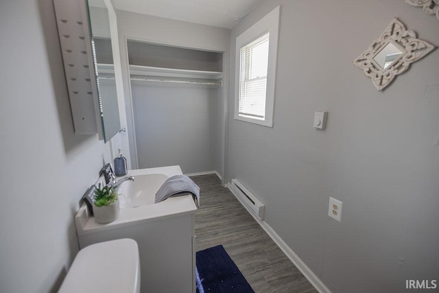 bathroom featuring wood finished floors, a sink, baseboards, a baseboard radiator, and toilet