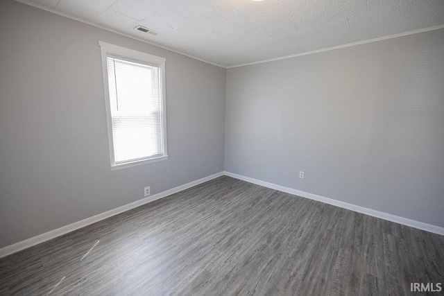 unfurnished room featuring baseboards, visible vents, dark wood-style floors, and ornamental molding
