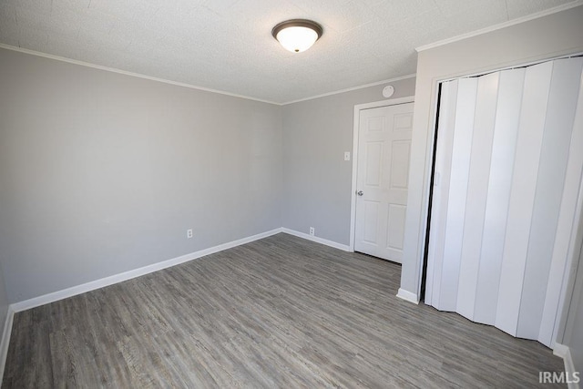 unfurnished bedroom with a closet, ornamental molding, wood finished floors, baseboards, and a textured ceiling