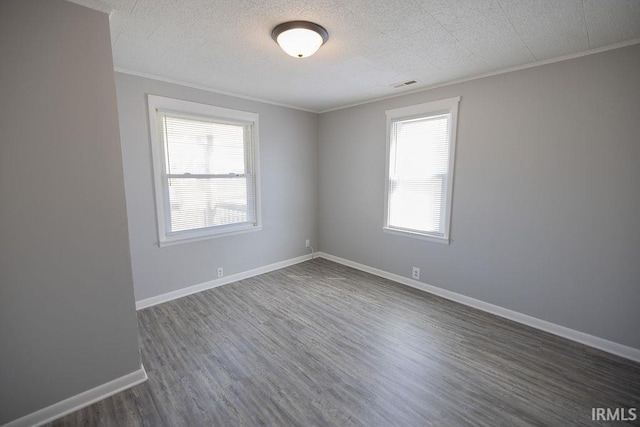 empty room featuring baseboards, dark wood finished floors, ornamental molding, and plenty of natural light