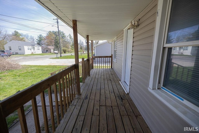 wooden deck featuring a yard, covered porch, and a residential view