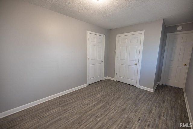 unfurnished bedroom featuring baseboards, a textured ceiling, and dark wood finished floors