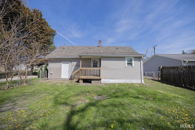 back of property with a lawn, a chimney, and a fenced backyard