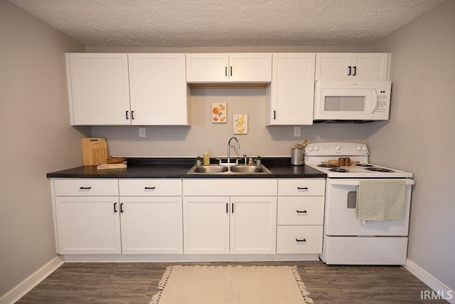 kitchen featuring dark wood finished floors, a sink, baseboards, white appliances, and white cabinetry