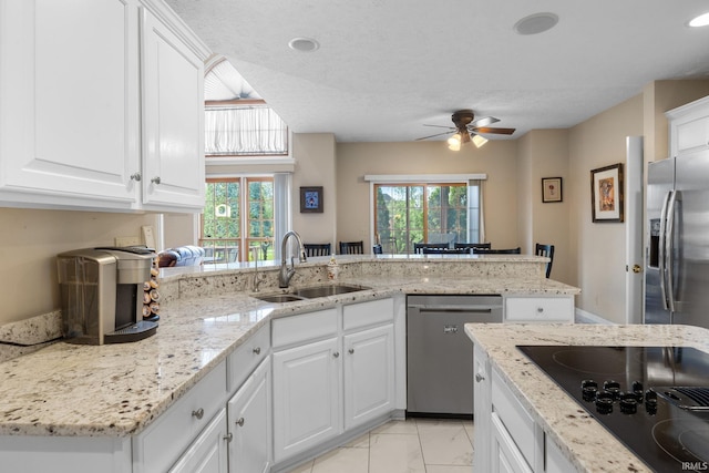kitchen featuring appliances with stainless steel finishes, a sink, marble finish floor, a ceiling fan, and a peninsula