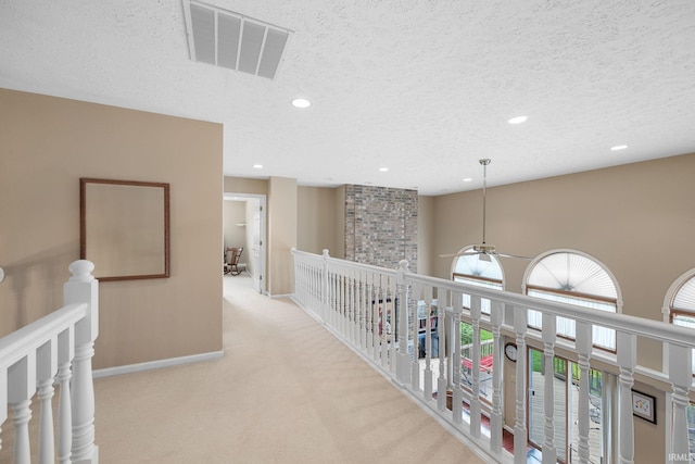 corridor featuring visible vents, a textured ceiling, carpet, and recessed lighting