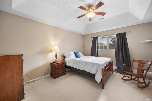bedroom with light colored carpet, a tray ceiling, a textured ceiling, and visible vents