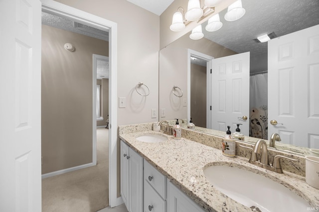 bathroom featuring double vanity, baseboards, a sink, and a textured ceiling