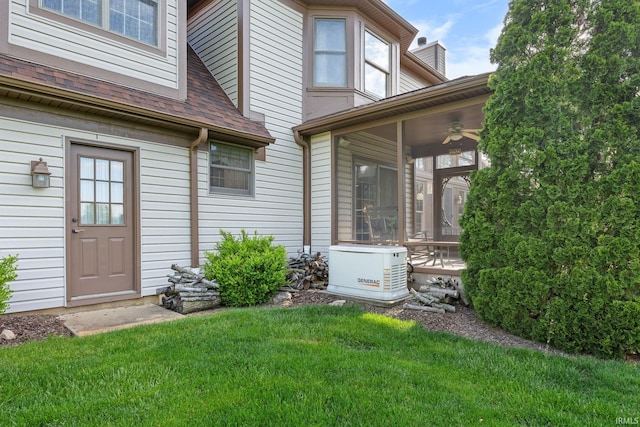 entrance to property with a lawn, a shingled roof, and ceiling fan