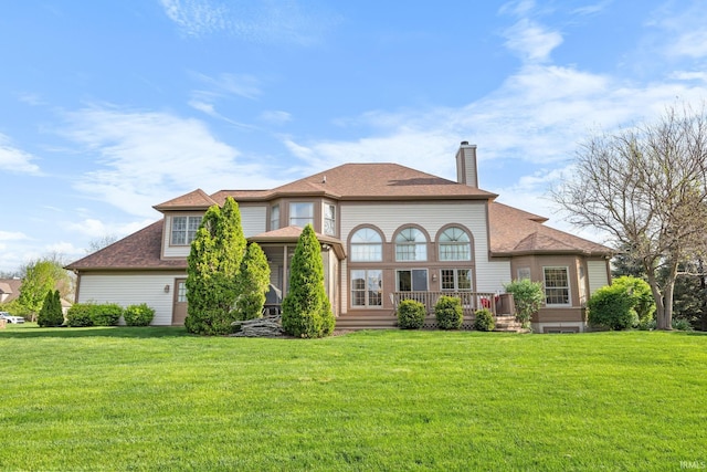 rear view of property with a shingled roof, a wooden deck, a yard, and a chimney