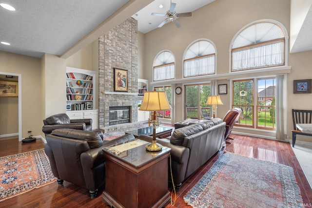 living room with wood-type flooring, baseboards, ceiling fan, and a fireplace