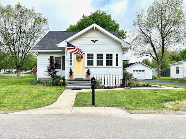 bungalow-style home with a garage, an outbuilding, a front lawn, and aphalt driveway