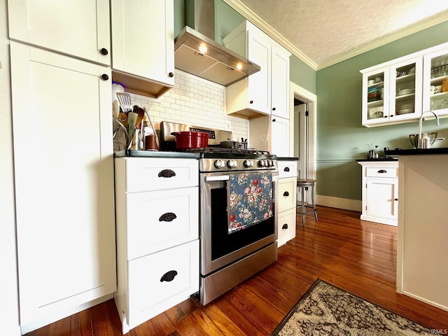 kitchen with wall chimney range hood, decorative backsplash, crown molding, dark countertops, and stainless steel gas range